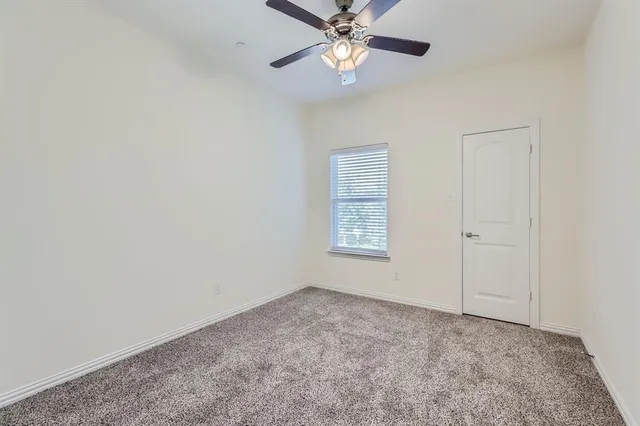 an empty room with a window and a chandelier fan