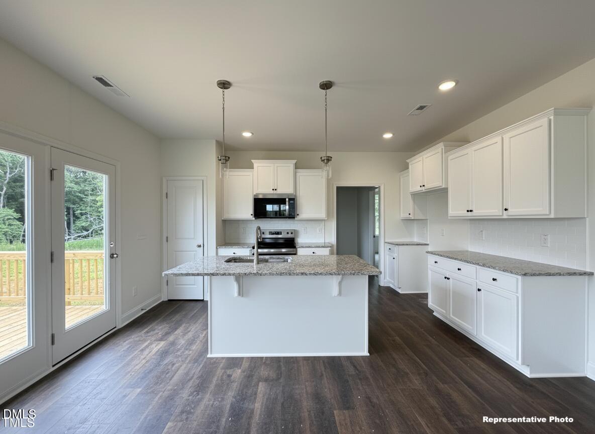 274 Longbow Drive Middlesex, NC 27557 - Photo 5 of 14 a kitchen with stainless steel appliances kitchen island granite countertop a stove a sink a refrigerator and white cabinets with wooden floor