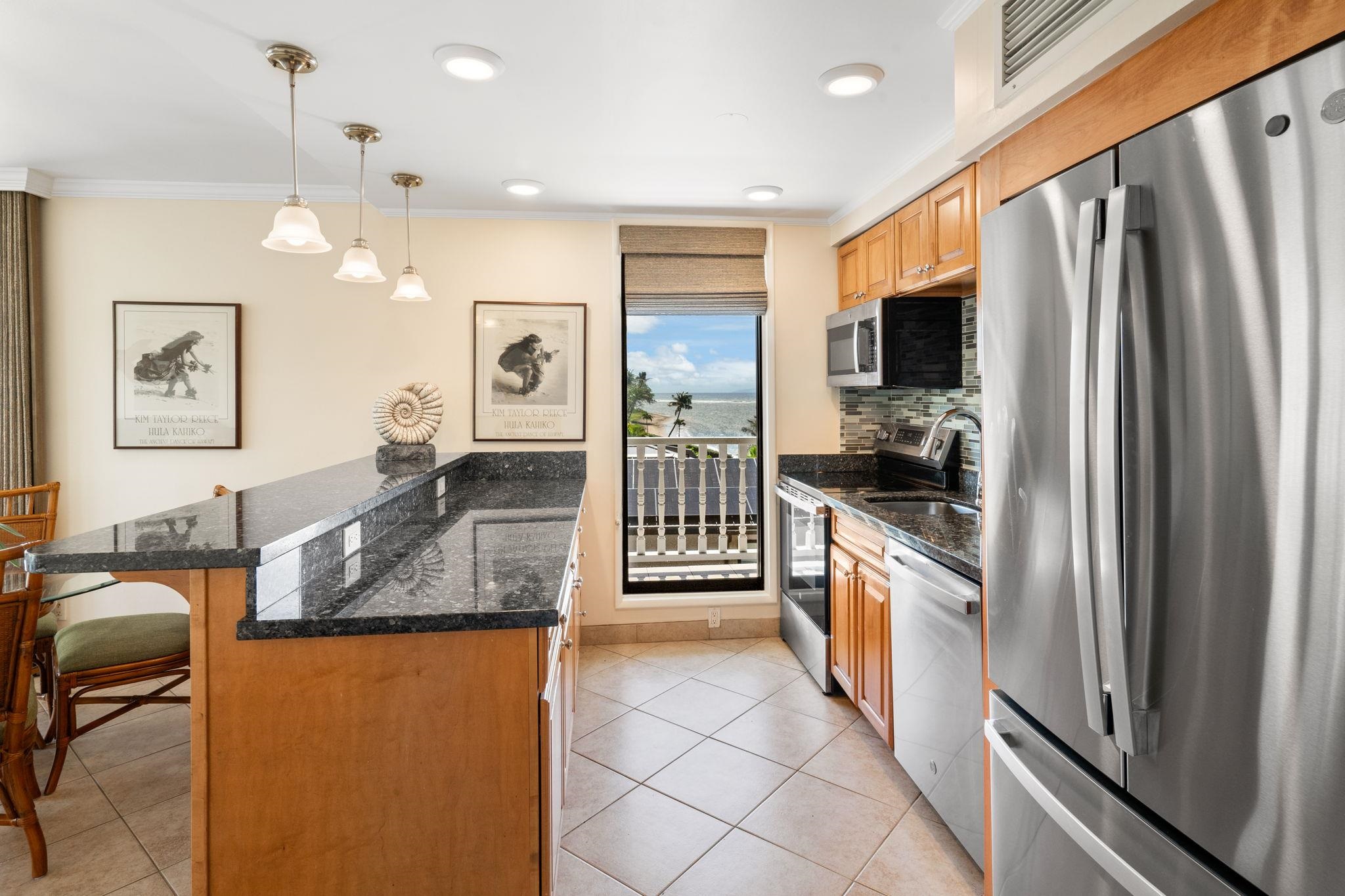 475 Front Street, Unit 402 Lahaina, HI 96761 - Photo 4 of 34 a large kitchen with granite countertop a refrigerator a stove a sink a dining table and chairs with wooden floor