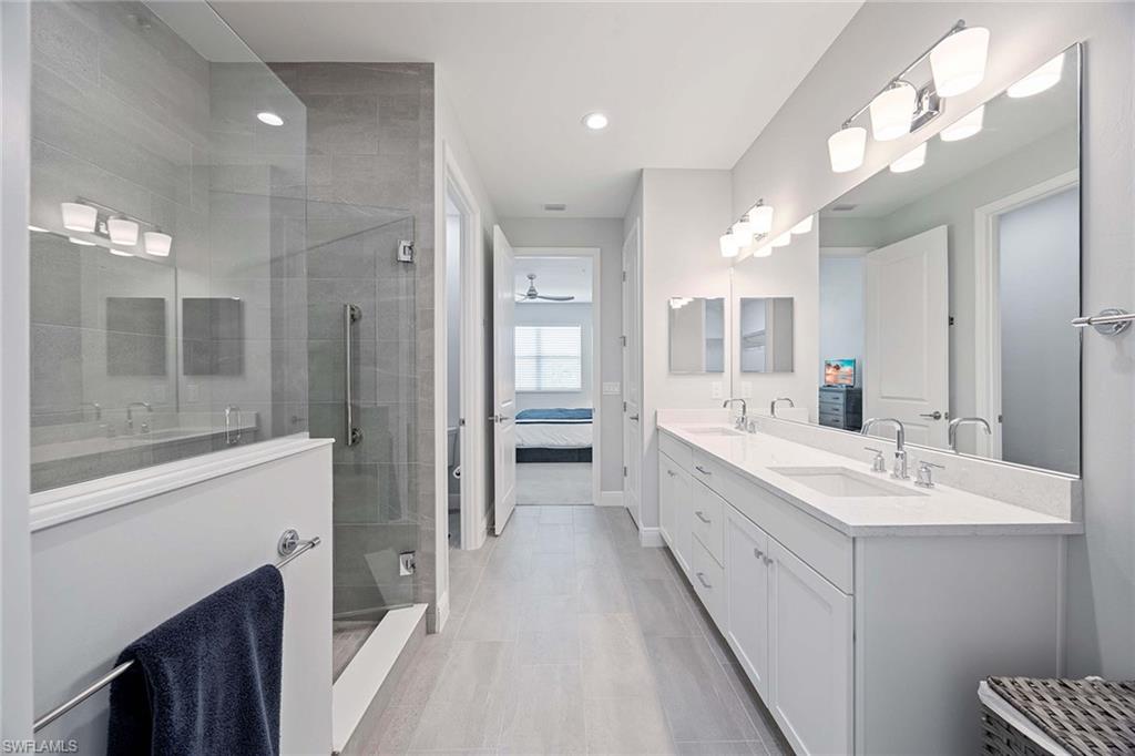 2603 Seychelles Circle, Unit 1505 Naples, FL 34112 - Photo 17 of 35 a large bathroom with a double vanity sink a toilet a mirror and shower