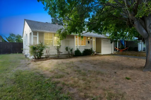 a view of a house with backyard and a tree