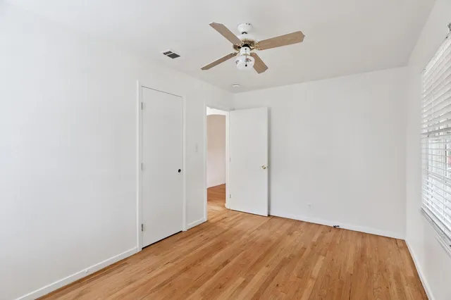 a view of a room with wooden floor ceiling fan and window