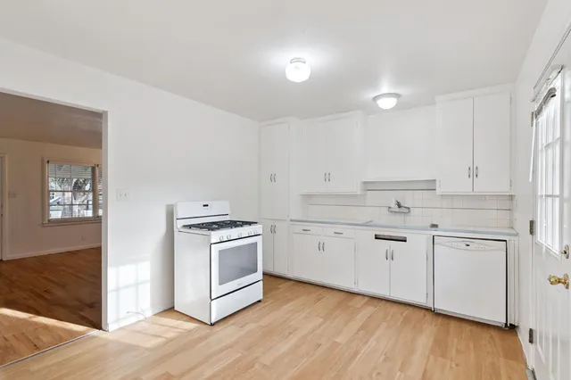 a kitchen with granite countertop white cabinets and stainless steel appliances