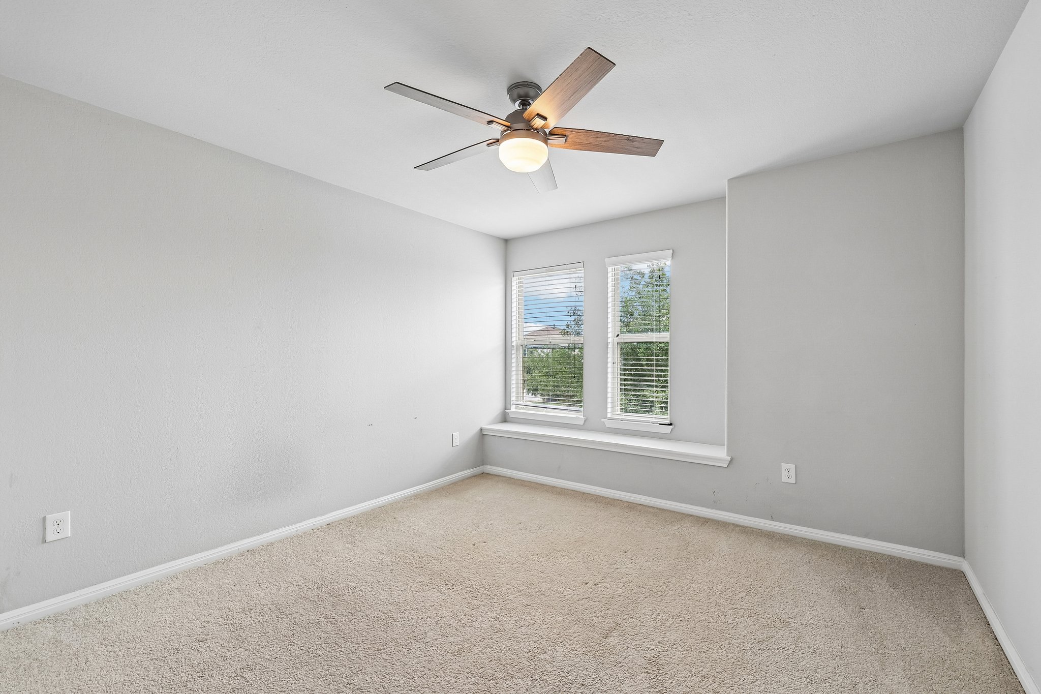 387 Guemal Road Buda, TX 78610 - Photo 26 of 39 Carpeted room featuring a ceiling fan with light fixture, two windows with blinds, a window sill, and light-toned wall paint