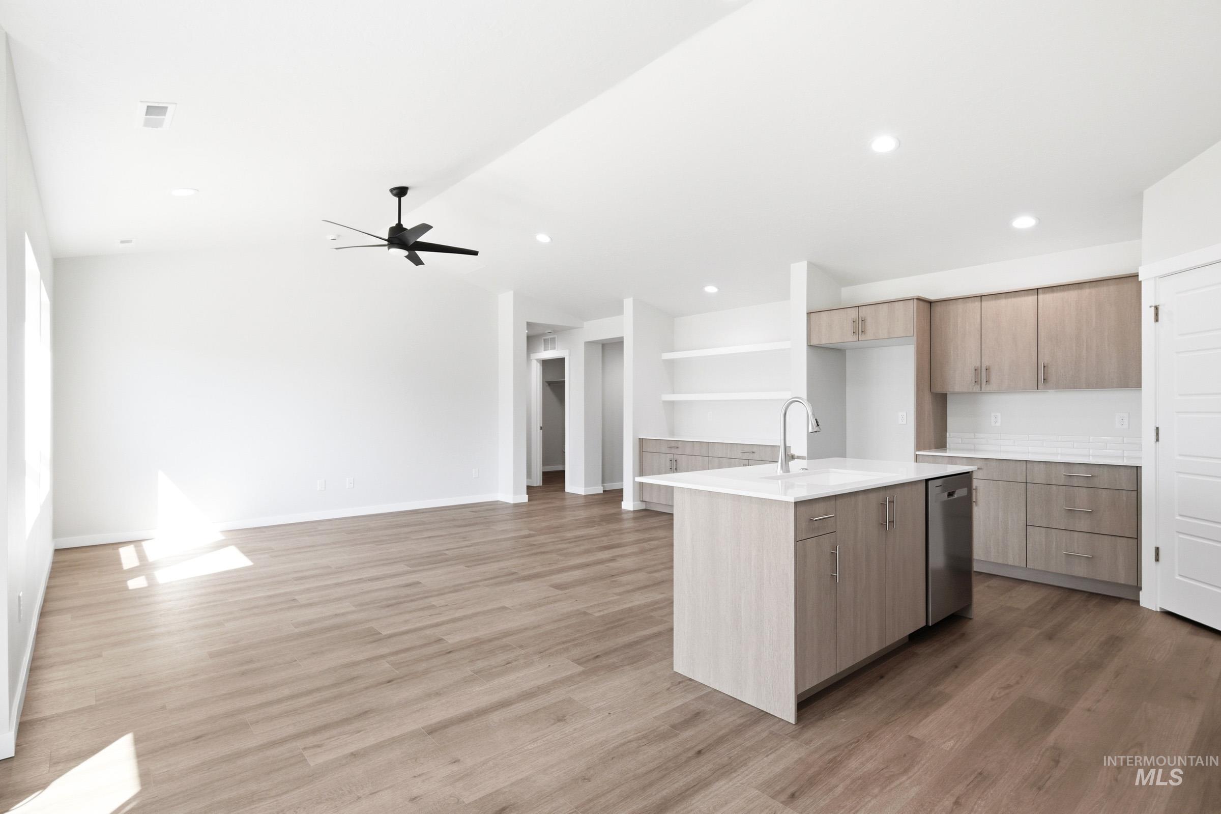 12877 Decatur Street Nampa, ID 83651 - Photo 10 of 22 Modern kitchen featuring a central island with a sink, stainless steel dishwasher, wood-finish cabinetry, and white countertops