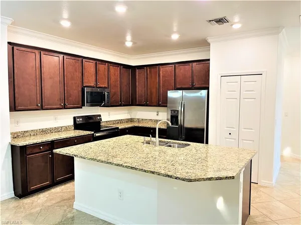 a kitchen with granite countertop wooden cabinets a refrigerator and a sink