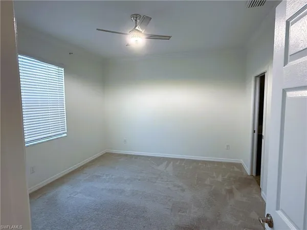 an empty room with a fan & a window