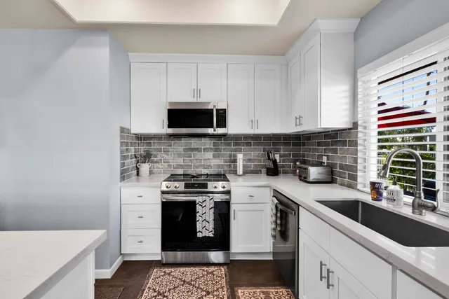 a kitchen with stainless steel appliances a sink a stove a microwave a sink and cabinets