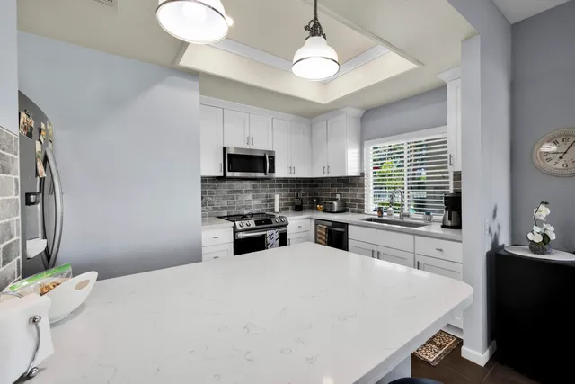 a kitchen with a refrigerator a stove a sink a microwave and dining table with wooden floor