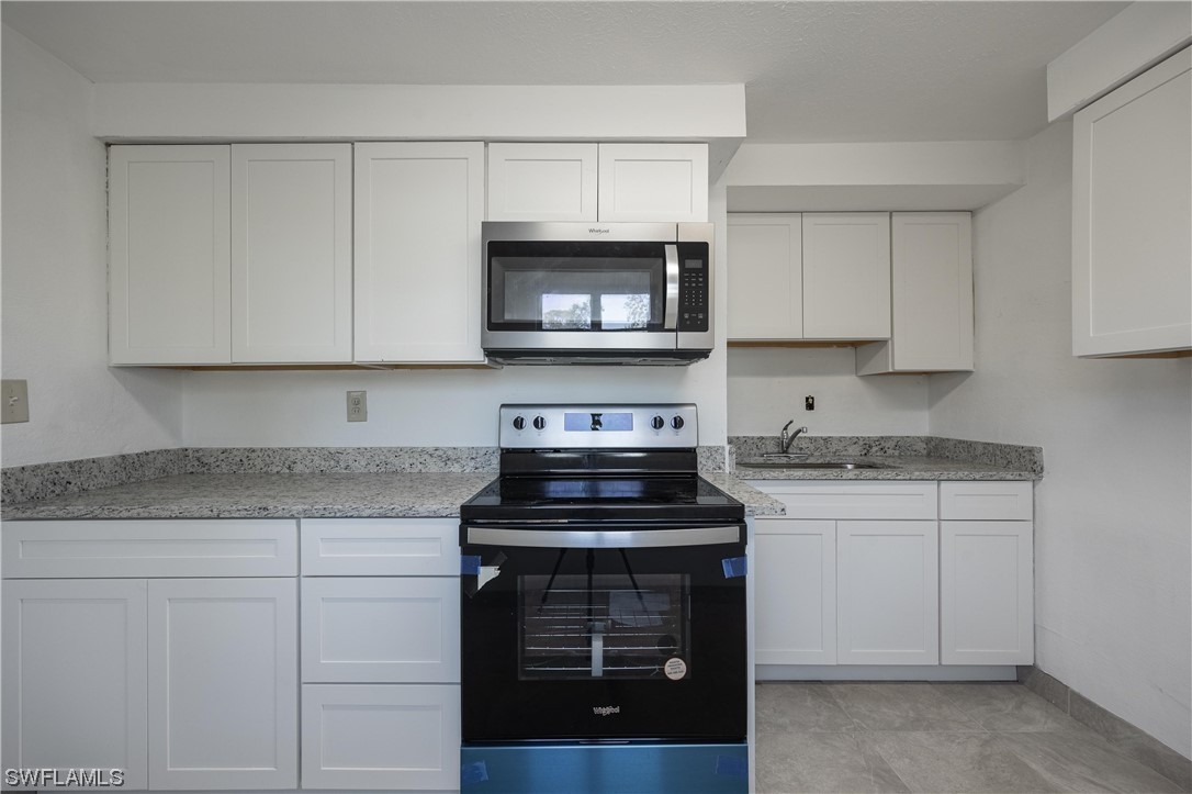 1338 Old Bridge Road North Fort Myers, FL 33917 - Photo 20 of 33 a kitchen with granite countertop white cabinets and a stove top oven