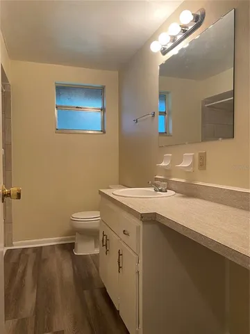 a bathroom with a granite countertop sink a toilet and a mirror
