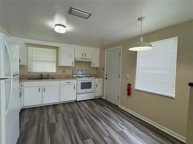 a kitchen with granite countertop white cabinets and white appliances