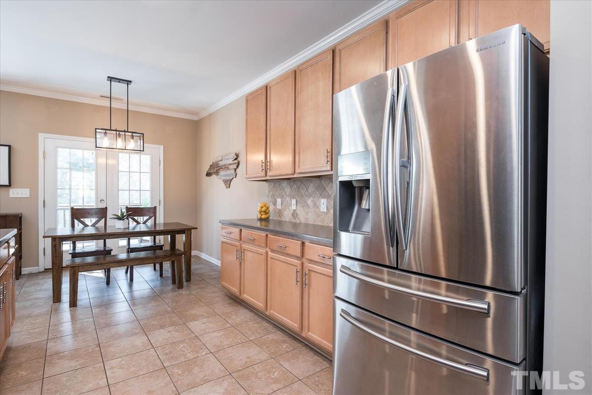 7724 Braefield Drive Raleigh, NC 27616 - Photo 9 of 27 a kitchen with stainless steel appliances granite countertop a refrigerator a stove a dining table and chairs with wooden floor