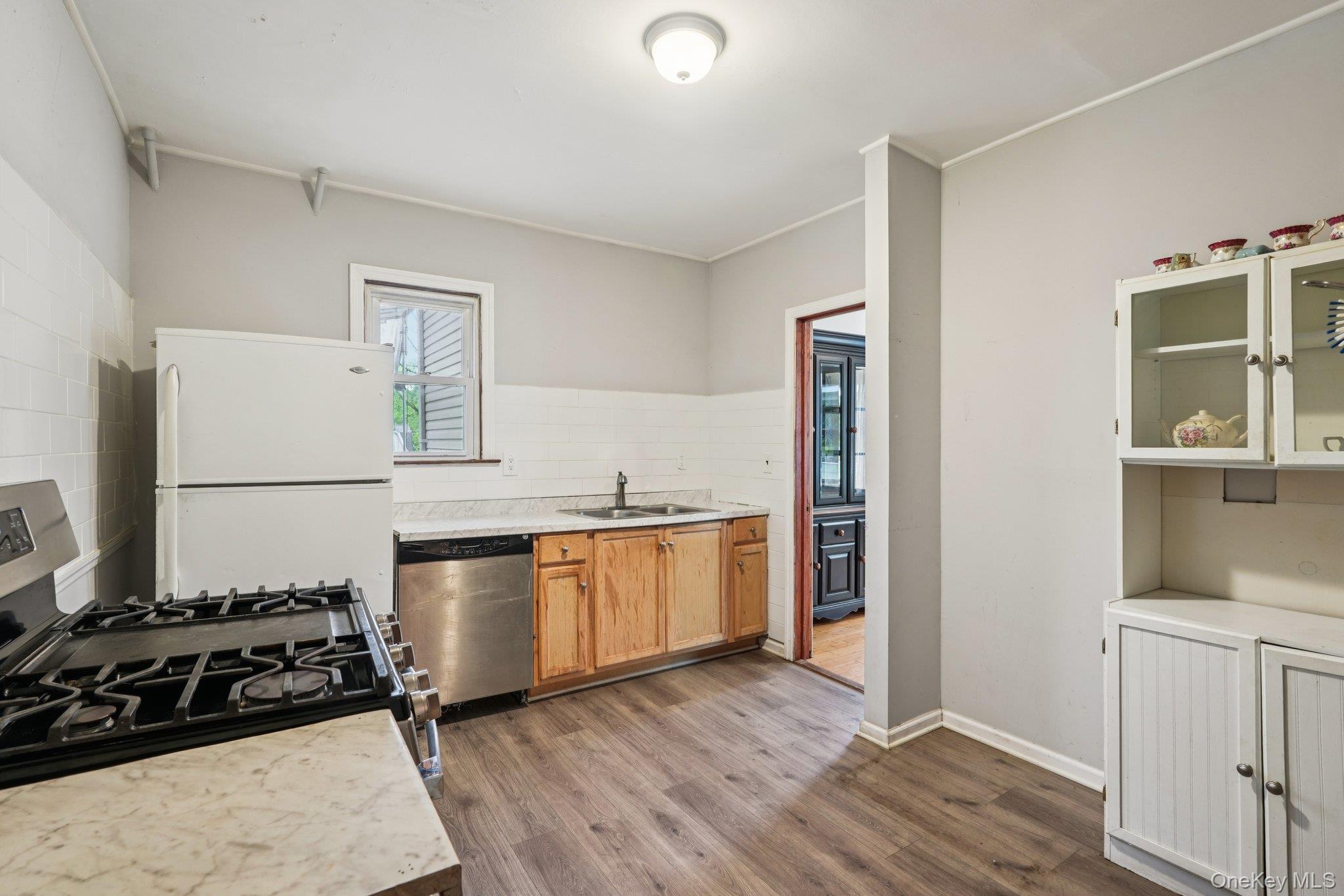 334 Union Avenue Peekskill, NY 10566 - Photo 6 of 20 Kitchen featuring stainless steel appliances, light countertops, wood finished floors, glass insert cabinets, and crown molding