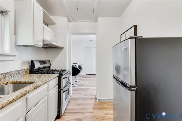 a kitchen with stainless steel appliances granite countertop a sink stove and white cabinets