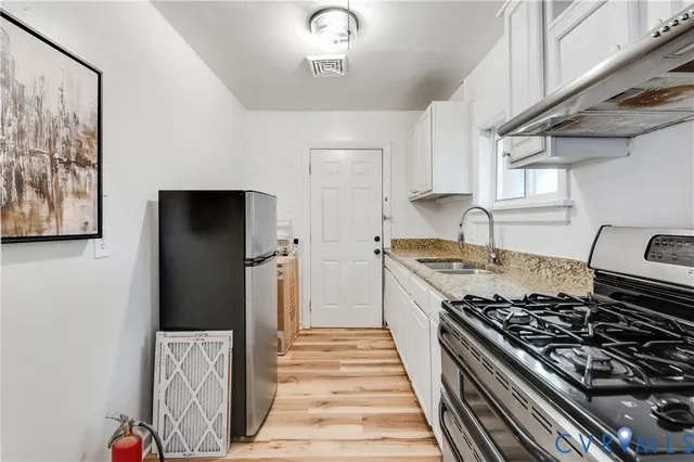 a kitchen with white cabinets and a stove top oven