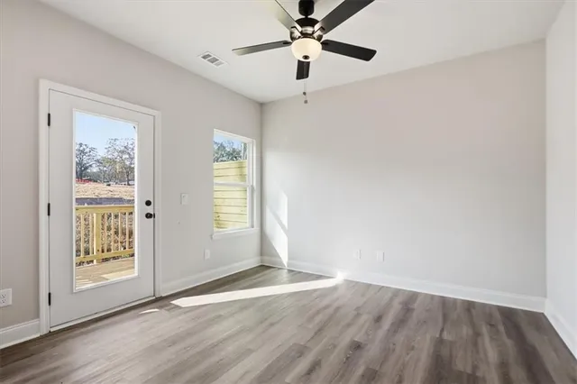 an empty room with wooden floor chandelier fan and windows