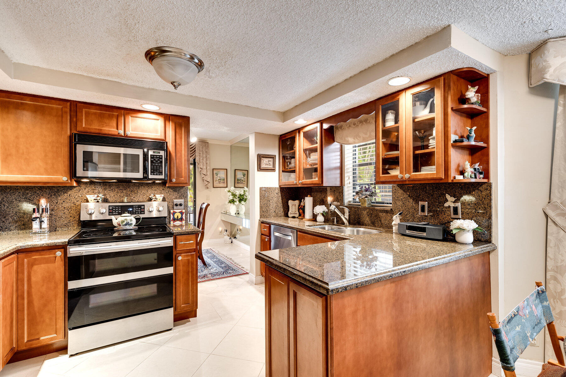 7771 La Mirada Drive Boca Raton, FL 33433 - Photo 12 of 38 a kitchen with stainless steel appliances granite countertop a stove top oven a sink dishwasher a dining table and chairs with wooden floor