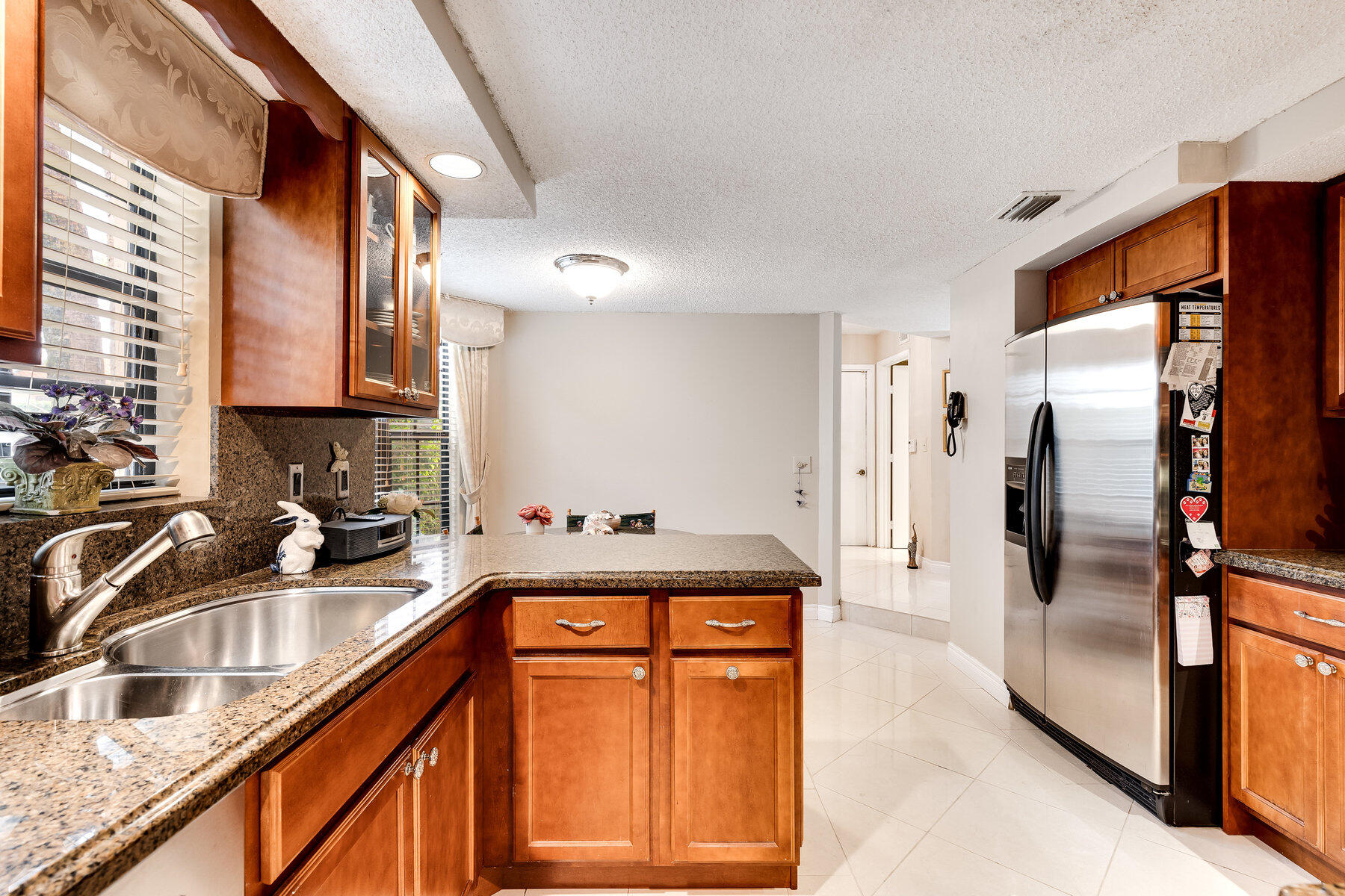 7771 La Mirada Drive Boca Raton, FL 33433 - Photo 14 of 38 a kitchen with granite countertop a refrigerator a sink a stove and wooden cabinets