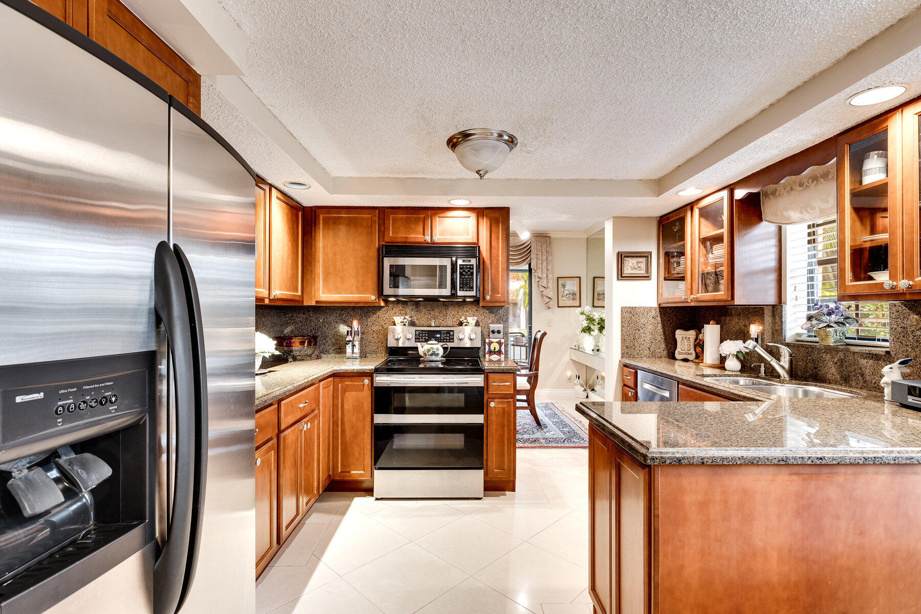 7771 La Mirada Drive Boca Raton, FL 33433 - Photo 10 of 38 a kitchen with stainless steel appliances granite countertop a refrigerator a stove and a sink with cabinets