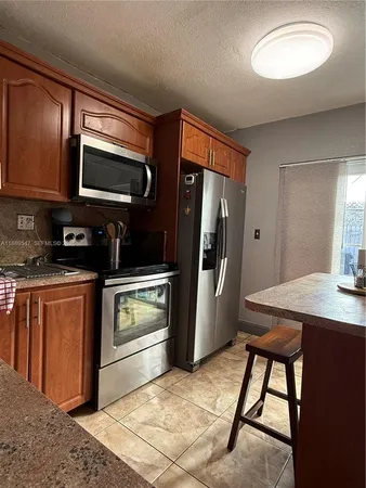 a kitchen with stainless steel appliances granite countertop a refrigerator and a stove top oven
