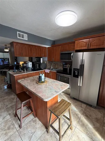 a kitchen with stainless steel appliances kitchen island granite countertop a table chairs and a refrigerator
