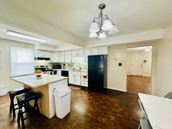a kitchen with a refrigerator a stove dining table and chairs
