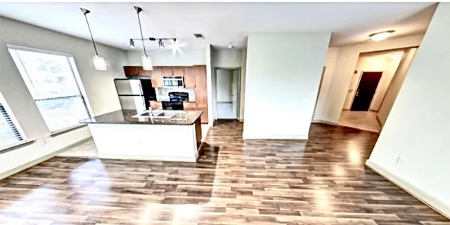 a view of a kitchen with kitchen island stainless steel appliances refrigerator microwave and wooden floor