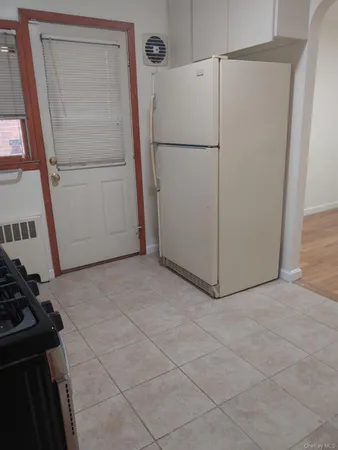 a view of a refrigerator in kitchen and white cabinets