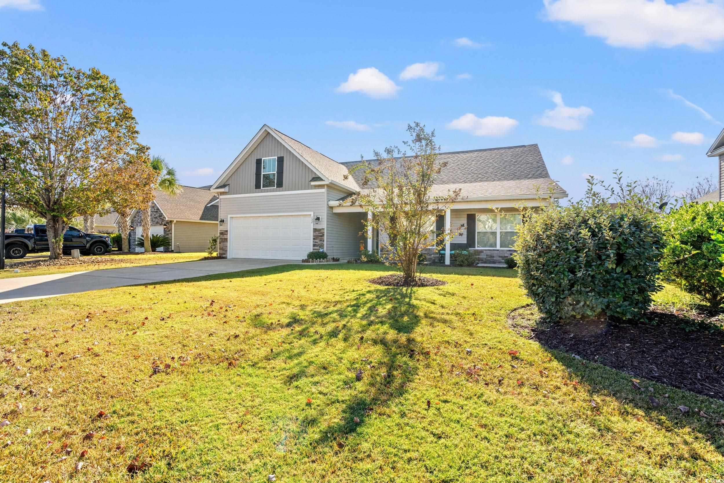 132 Fox Den Drive Murrells Inlet, SC 29576 - Photo 26 of 35 View of front of property featuring driveway, stone siding, a front lawn, a garage, and covered porch
