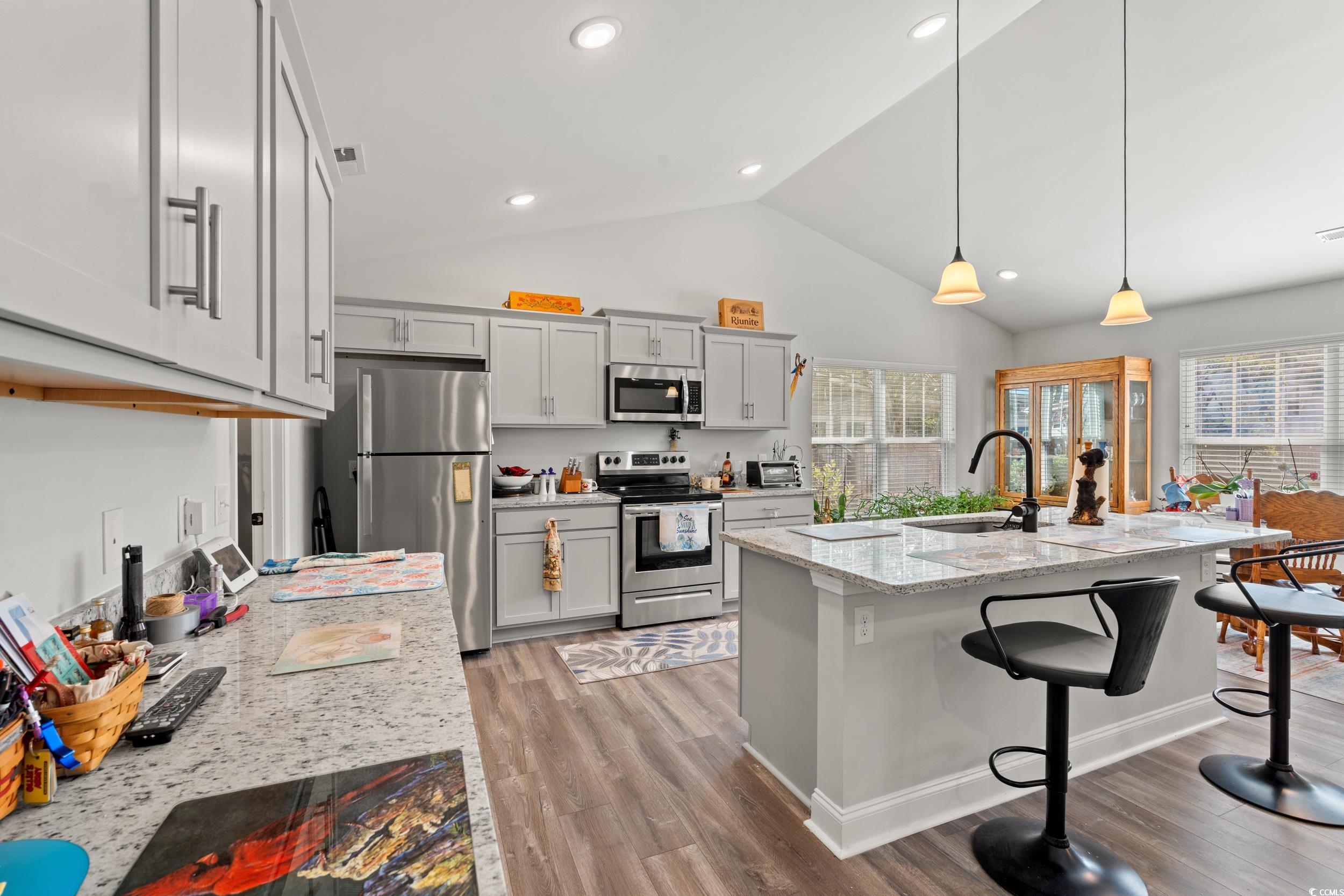 132 Fox Den Drive Murrells Inlet, SC 29576 - Photo 6 of 35 Kitchen with light stone counters, stainless steel appliances, a kitchen breakfast bar, pendant lighting, and light wood-style floors