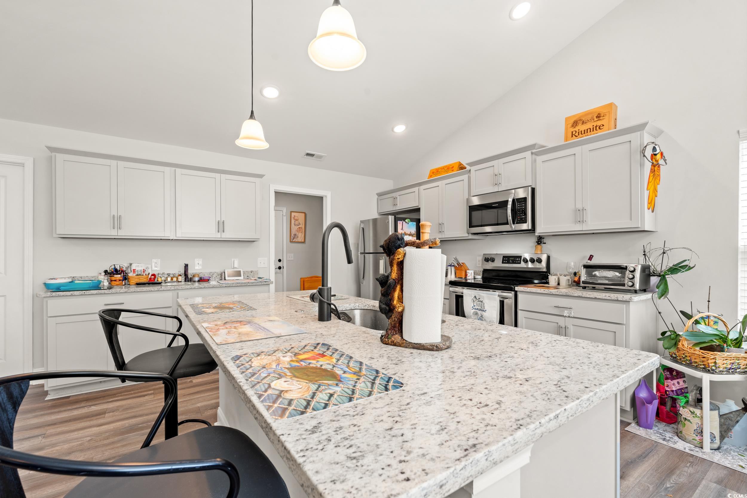 132 Fox Den Drive Murrells Inlet, SC 29576 - Photo 7 of 35 Kitchen with a breakfast bar, decorative light fixtures, light wood-style floors, lofted ceiling, and stainless steel appliances