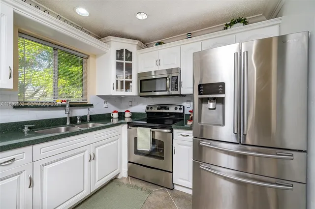 a kitchen with stainless steel appliances granite countertop a refrigerator sink and stove