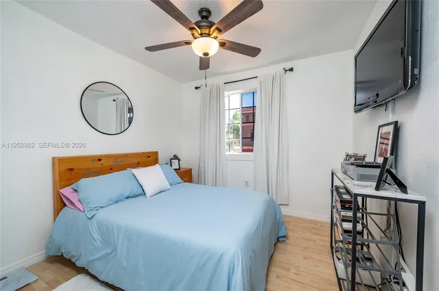 a bedroom with a bed a flat tv screen and a dresser