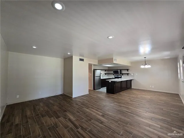 a kitchen with stainless steel appliances granite countertop a stove a refrigerator and a wooden floor