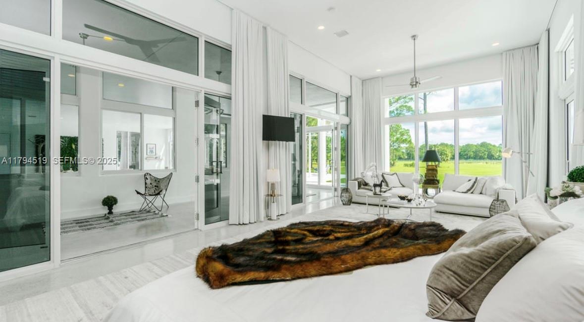 1901 Southeast Ranch Road South Jupiter, FL 33478 - Photo 18 of 53 a spacious bedroom with a bed a glass window and a glass door