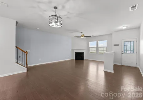 a view of an empty room with wooden floor and windows
