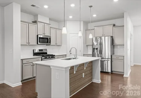 a kitchen with stainless steel appliances a refrigerator stove a sink and white cabinets