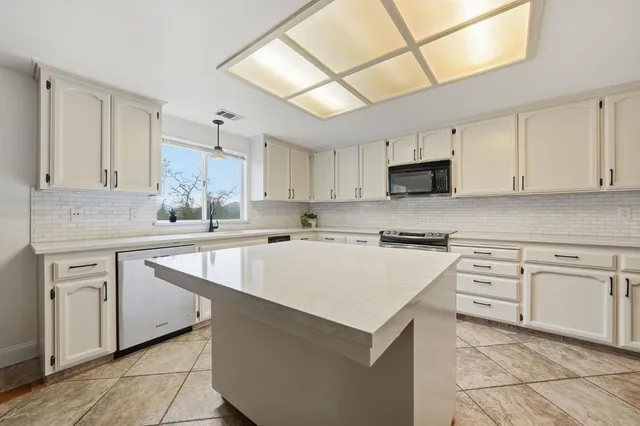 a kitchen with kitchen island a white cabinets and refrigerator