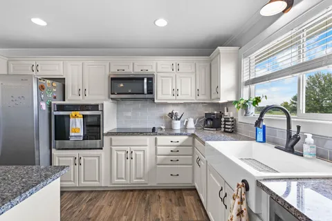 a kitchen with stainless steel appliances granite countertop a stove a sink and a microwave