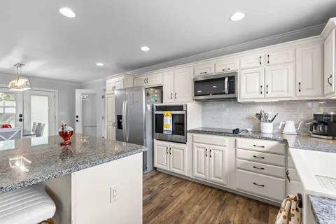 a kitchen with granite countertop a refrigerator stove top oven and sink