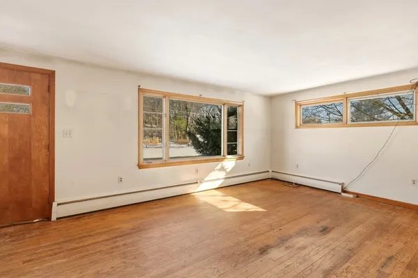 an empty room with wooden floor and windows
