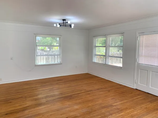 a view of an empty room with wooden floor and a window