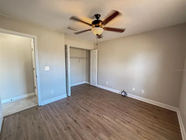 an empty room with wooden floor and fan