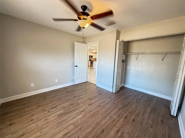 an empty room with wooden floor and a ceiling fan