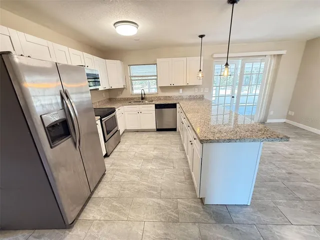 a kitchen with stainless steel appliances granite countertop a refrigerator a sink dishwasher and a stove