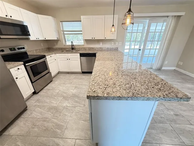 a kitchen with stainless steel appliances granite countertop a stove top oven a sink a counter space and cabinets