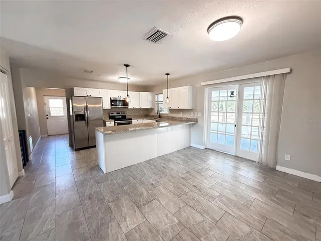 a large kitchen with a lot of white cabinets and stainless steel appliances