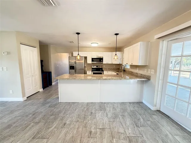 a large kitchen with stainless steel appliances a large counter top a stove and a refrigerator