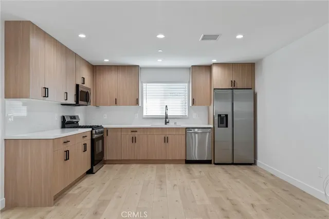 a large kitchen with stainless steel appliances granite countertop a stove a sink and a refrigerator